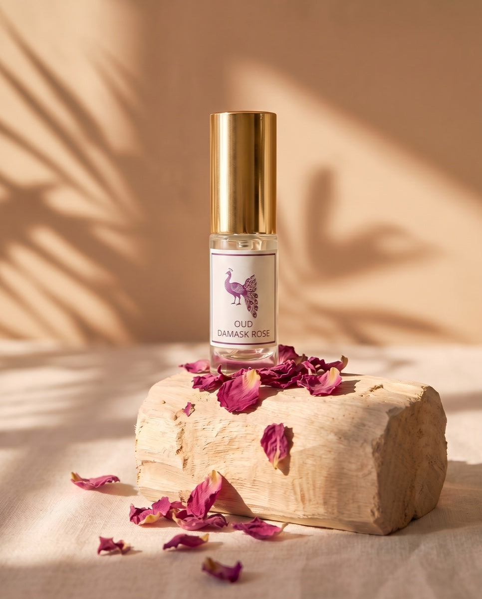 Oud Damask Rose eau de parfum with damask-rose petals on sandalwood in golden light